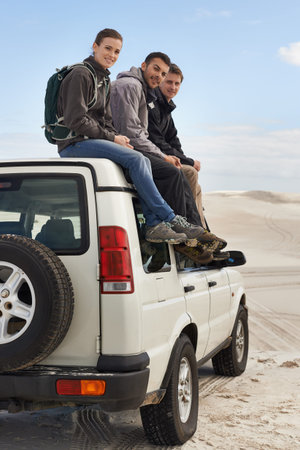 We love roadtripping with friends. a group of friends sitting on their car while on a roadtrip.