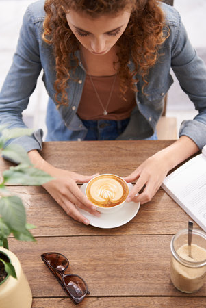 Relaxing with a fresh cup of coffee. a young woman drinking coffee at a cafe.の写真素材
