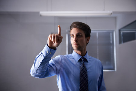 New technology in the workplace. A young businessman using a digital interface.の写真素材