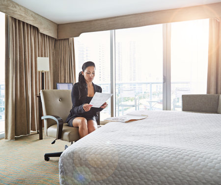 The hotel that caters to all of her corporate needs. a young businesswoman working in her hotel room.の写真素材
