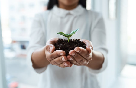 A plant grown is a life saved. an unrecognizable businesswoman holding a plant growing out of soil.