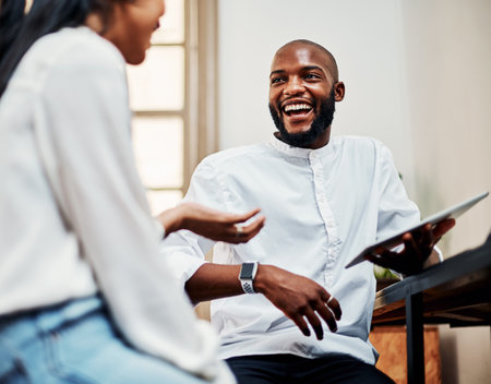 Cracking the occasional joke keeps the creativity flowing. a young businessman and businesswoman using a digital tablet during a meeting in a modern office.の写真素材