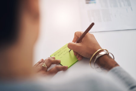 I better make a note of this. an unrecognizable businesswoman sitting alone in her office and writing on a post-it.の写真素材