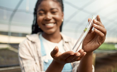 Happy farmer holding a plant sample. Young botanist holding a test tube sample. Young farmer...