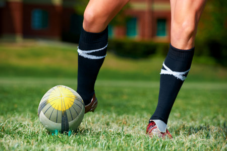 Rugby, feet and man with a sports ball outdoor on a pitch for action, goal or score. Male athlete person playing in sport competition, game or start training for fitness, workout or kick exerciseの写真素材