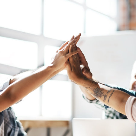 Productivity is in the hands of a team. a group of colleagues giving each other a high five during a...