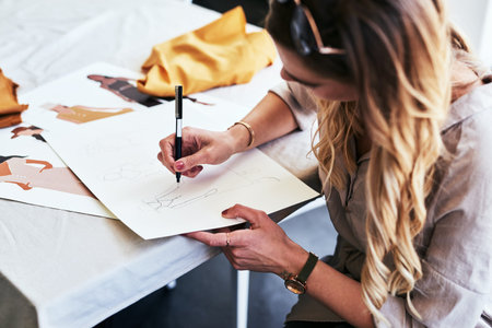 She has excellent drawing skills. a fashion designer working on new sketches at her desk.