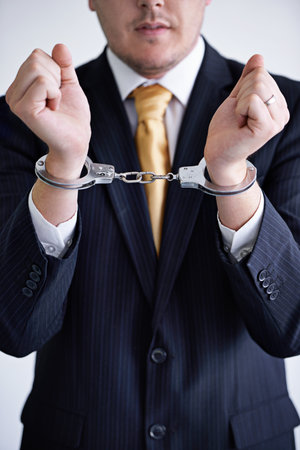 Brought to justice. a businessman wearing handcuffs.