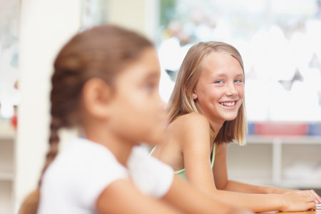 A happy and confident student with a bright future. Sweet young girl smiling past one of her classmates at the camera - copyspace.の写真素材