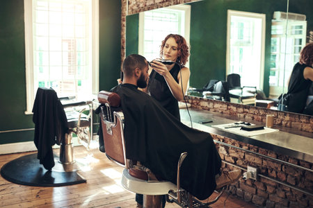 Change brings about confidence. an attractive young hairdresser standing and styling her clients hair in her salon.の写真素材