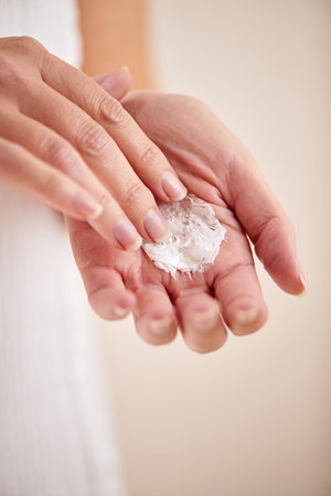 Adding some moisture to her skin. Cropped studio shot of a mature woman applying moisturizer.の写真素材