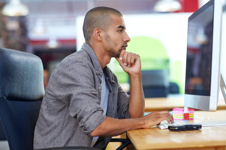 The daily grind. a designer at work on a computer in an office.