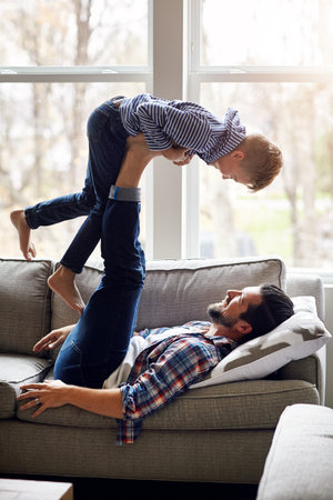 Dad always ensures all his days are filled with fun. a father and his little son having fun at home.の写真素材
