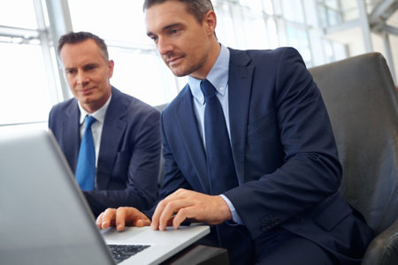 Laptop, corporate lounge and business people teamwork on finance portfolio review, stock exchange analysis or banking. Crypto, online research and professional men working on financial stocks tradingの写真素材