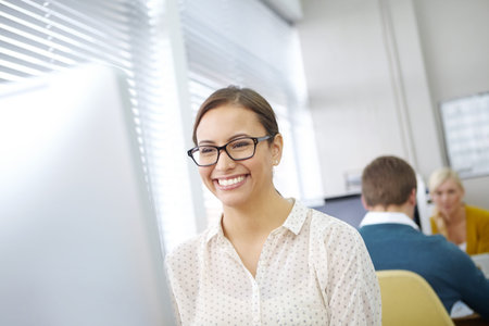 I aim to do the best I can. an attractive young office worker sitting at her desk and working on a...