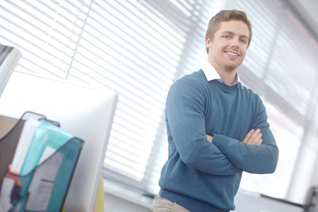 Tackling his work with a smile. Portrait of a handsome young businessman standing in his office.
