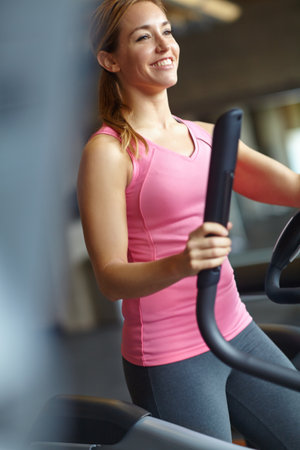 Im making great progress. A beautiful young woman working out at the gym.の写真素材