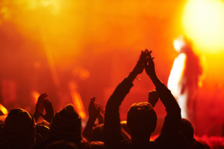 Night brings the party. Rear view of an audience with hands raised at an outdoors festival.