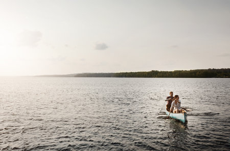 Row together, row further. a young couple going for a canoe ride on the lake.の写真素材