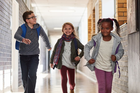 Racing to class. elementary school kids running in the corridor at school.の写真素材