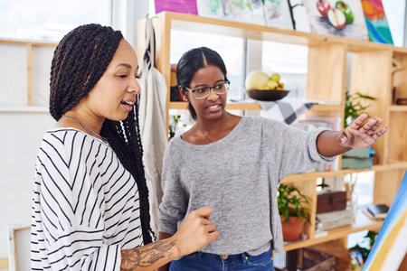 Fall in love with visual arts. two young women discussing something on a canvas in a art studio.の写真素材