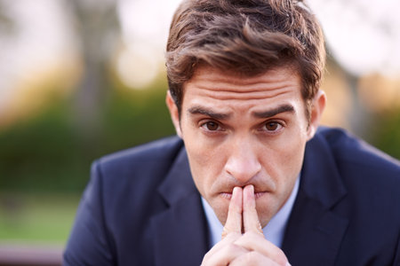 Hes got a lot on his mind. a serious businessman frowning while sitting outside.の写真素材