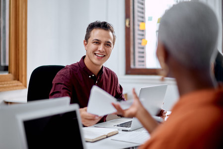 I saved a copy for you. a young businessman passing on paperwork to a colleague in an office.