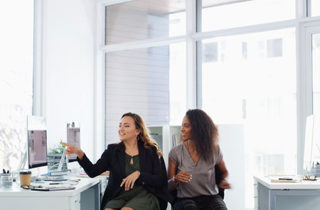 What is your opinion on this. two young businesswomen using a computer together in a modern office.の写真素材