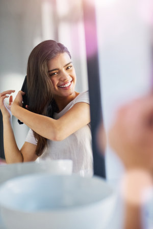 No tangles here. a beautiful young woman brushing her hair in the bathroom at home.の写真素材
