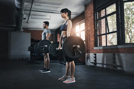 We love the gym. a young man and woman working out with weights at the gym.の写真素材