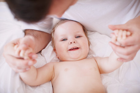 Holding onto her little hands. A devoted young dad holding onto his baby daughters hands.