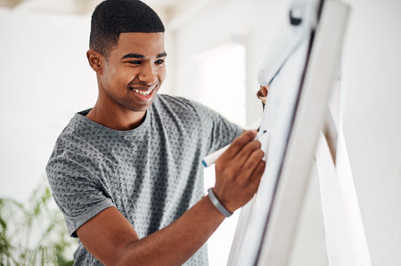 Laying out his objectives for the day. a young businessman writing notes on a whiteboard in an office.の写真素材