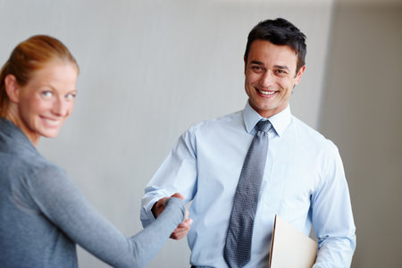 Making good business acquaintances. A young businessman shaking hands with a female coworker.の写真素材