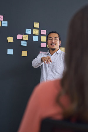 Meeting, brainstorming and presentation with team, man speaker and sticky note with leadership at...