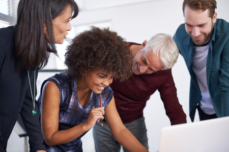 Success would make anyone smile. a group of architects using a laptop to work on their designs.の写真素材