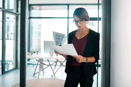 Documents, reading and business woman in workplace for data analysis, statistics report and spreadsheet review or budget. Professional worker, accountant or person with paperwork, accounting or taxesの写真素材
