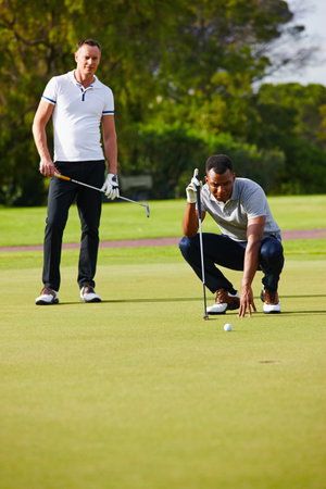 Improving their handicap one ball at a time. two golfers watching as the ball approaches the hole.の写真素材