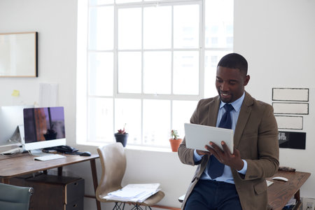 Business, black man and tablet in office for planning, connection and internet research in agency. Happy male worker, digital technology and scroll website for online information, insight and appの写真素材