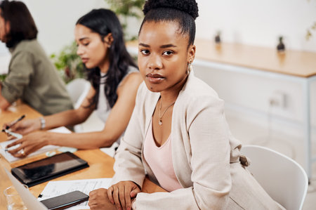 Youve got to stay focused to achieve your objectives. Portrait of a young businesswoman sitting in an office with her colleagues in the background.の写真素材
