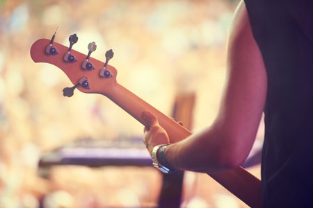 Giving an electric performance. a guitarist performing on stage in front of a massive crowd.