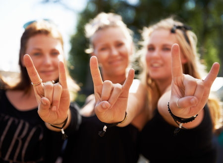Keep on rocking. Three young girls giving you a rock and roll sign at a music festival.の写真素材