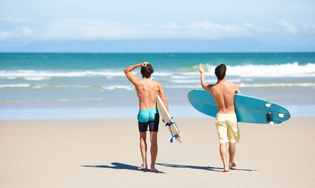 Excited for some surfing. Two friends at the beach getting ready to head into the water for a surf.の写真素材