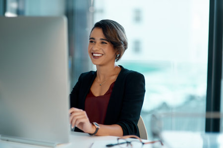 Computer, happy and business woman with online solution, software management and reading company review. Working, website planning and smile of professional worker or person on desktop pc in officeの写真素材