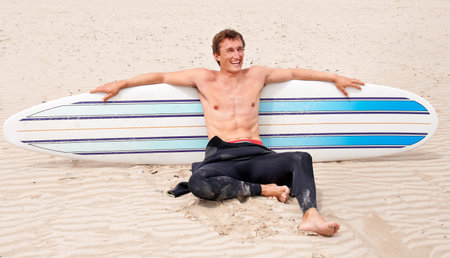 Surfing is a way of life. A young male surfer getting ready to go for a surf on a hot summers day.の写真素材