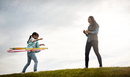 She spins my world around. a mother watching her daughter spinning the hula hoop.