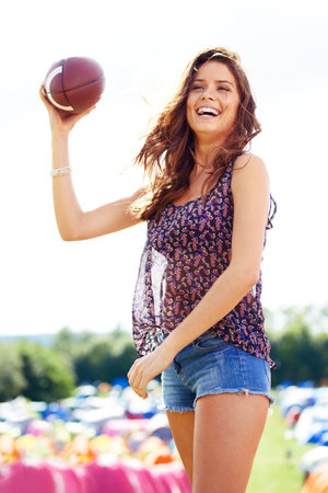 Wanna catch. an attractive young woman holding a football at a campsite.の写真素材