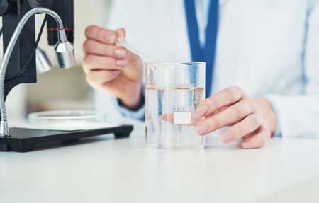I hope this works. Closeup of an unrecognizable scientist mixing chemicals together at their desk inside of a laboratory.の写真素材