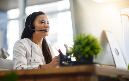 Communication, customer services or woman in call center consulting, speaking or talking at help desk. Virtual assistant, friendly or sales consultant in telemarketing or telecom company officeの写真素材