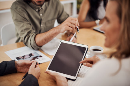 Lets browse around and see what we find online. Closeup shot of a group of businesspeople using a digital tablet during a meeting in an office.の写真素材