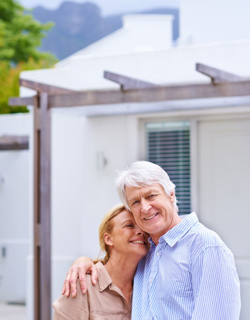 Her happiness is my number one priority. Portrait of an elderly couple standing in front of their house.の写真素材
